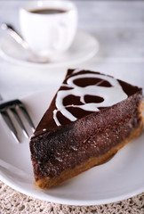 Piece of chocolate cake on plate and cup of tea on table