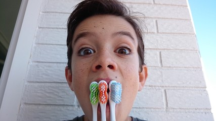 Niño con cepillos de dientes en la boca