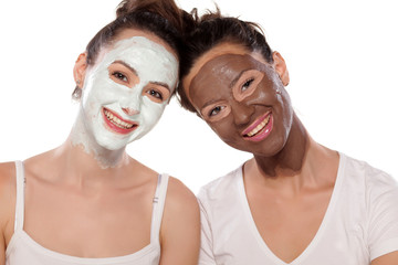 two smiling young women with masks posing on white