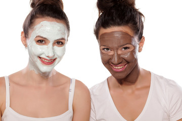 two smiling young women with masks posing on white