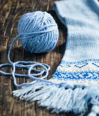 Ball of yarn and knitted scarf on wooden background