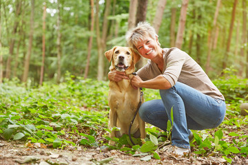 Labrador Retriever mit Seniorin im Wald