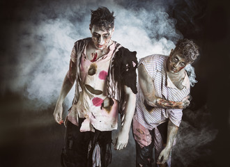 Two male zombies standing on black smoky background - obrazy, fototapety, plakaty