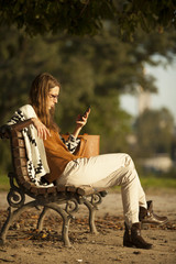 Fashion Young Girl Using Smart Phone On Bench In Park