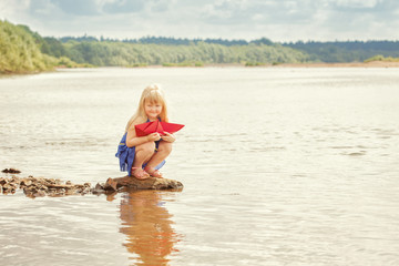 Cute little girl wants to run paper boat in lake