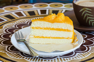 orange cake and late  cofee cup on a table
