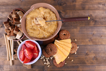 Fondue, slices of cheese, tomatoes and biscuits