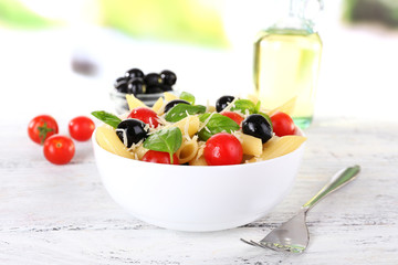 Pasta with tomatoes, olives and basil leaves in bowl