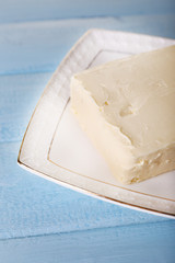 Fresh butter on plate, on wooden background