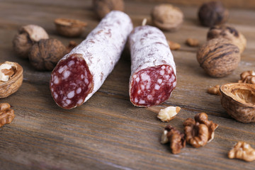 French salami and walnuts on wooden background