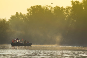 Rybacy zbierający sieci z połowem na rzece