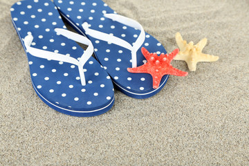 Fototapeta na wymiar Flip flops on sea sand background
