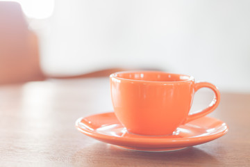 Mini orange coffee cup on wooden table