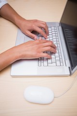 Hands using laptop at desk