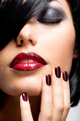 Face of a woman with beautiful dark nails and sexy red lips