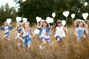 portrait of a little girls in a field with white balloons