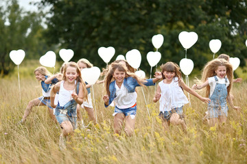 Fototapeta premium portrait of a little girls in a field with white balloons