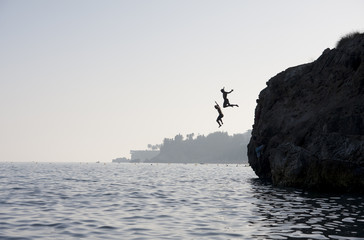People jumping into the water from cliff - Powered by Adobe