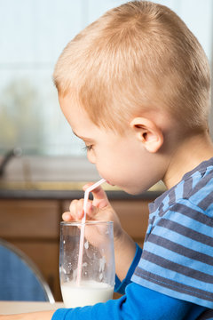 Cute little boy drinks milk using a drinking straw