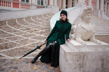 Woman in a green coat posing on stairs