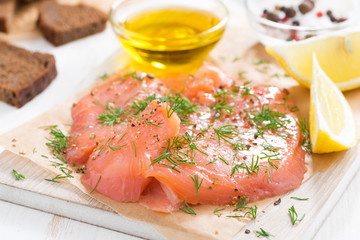salted salmon, bread and ingredients on a wooden board, close-up