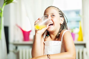 Crédence de cuisine en verre imprimé Jus Mixed race girl drinking orange juice, at home