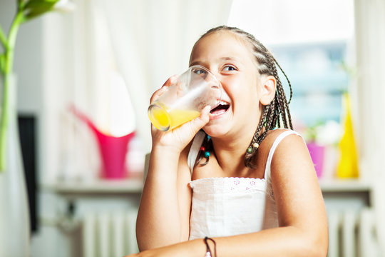 Mixed race girl drinking orange juice, at home