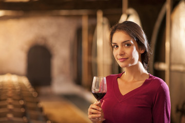 Professional winemaker female tasting a glass of red wine in his
