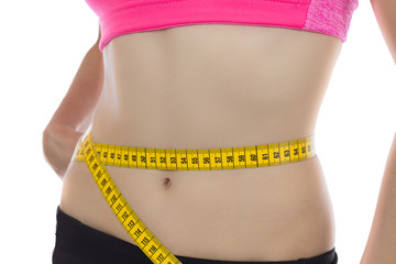 Fit woman measuring her waistline with a tape
