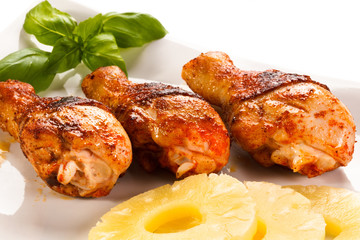 Grilled chicken legs and vegetables on white background