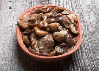 Salty mashrooms in a bowl on a old wooden board