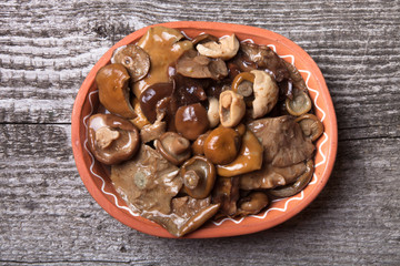 Salty mashrooms in a bowl on a old wooden board