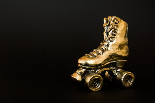 Golden Roller Skate Against Black Background