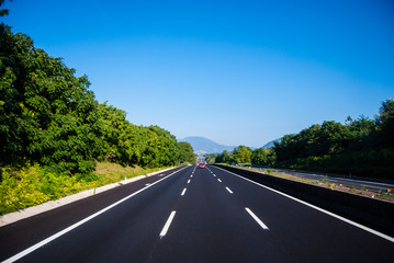 asphalt road through the green field and clouds on blue sky in s