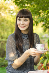 Девушка отдыхает в саду, с чашкой чая