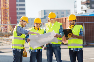 group of builders with tablet pc and blueprint