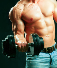 Unknown muscular man working out with dumbbells over black