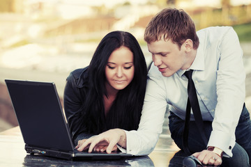 Young business couple using laptop outdoor