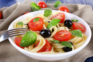 Spaghetti with tomatoes, olives and basil leaves