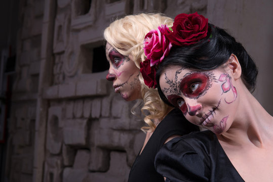 Portrait of two young girls in black dresses with Calaveras make