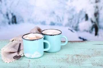 Cups of tasty hot cocoa, on wooden table, on light background
