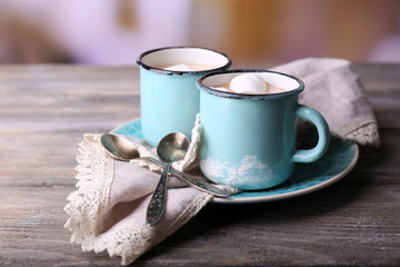 Cups of tasty hot cocoa, on wooden table, on light background