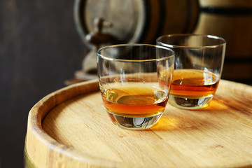 Glasses of brandy in cellar with old barrels