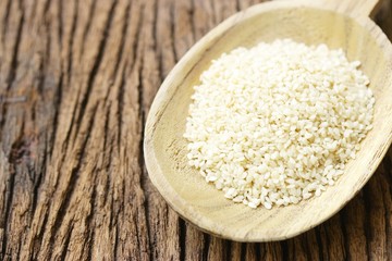 White Sesames in wooden spoon on wooden table
