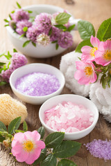 Fototapeta na wymiar spa with pink herbal salt and wild rose flowers clover