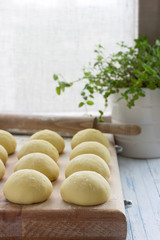 Balls of fresh homemade dough on floured wooden board