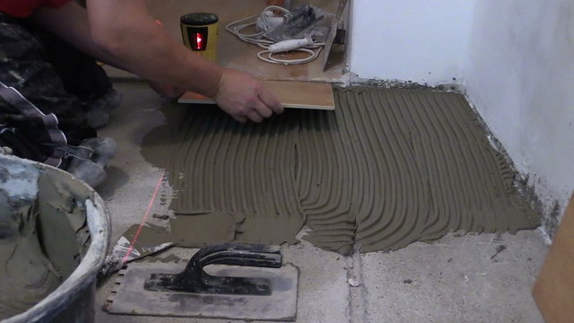 Master worker man lay ceramic floor tiles in kitchen
