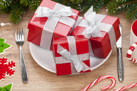 Gift boxes on plate, fir tree and christmas decor