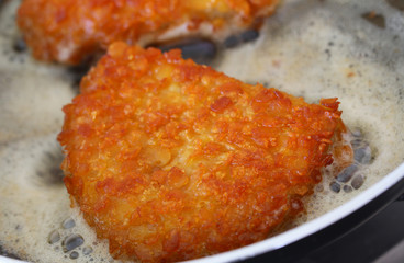 Crispy chicken fillet in the frying pan, closeup