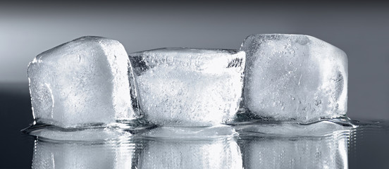 Three ice cubes on grey gradient background.